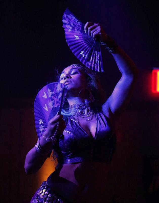 A specialty performer in dramatic violet stage lighting